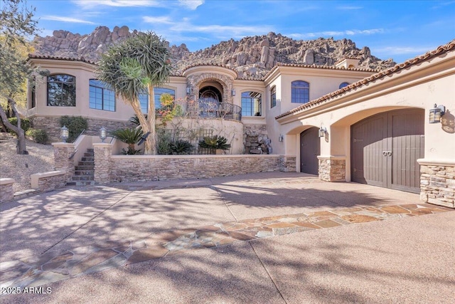 mediterranean / spanish house with driveway, stone siding, stairs, a mountain view, and stucco siding