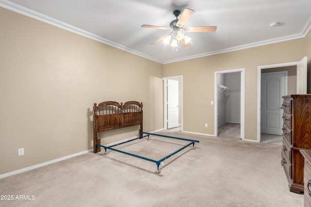 bedroom with a closet, a walk in closet, ornamental molding, ceiling fan, and light colored carpet