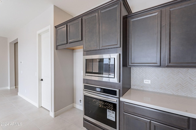 kitchen featuring dark brown cabinets, light tile patterned flooring, appliances with stainless steel finishes, and tasteful backsplash