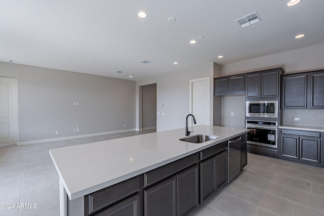 kitchen with a kitchen island with sink, sink, light tile patterned floors, and stainless steel appliances