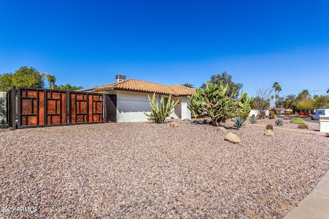 view of front of house featuring a gate, a tiled roof, and stucco siding