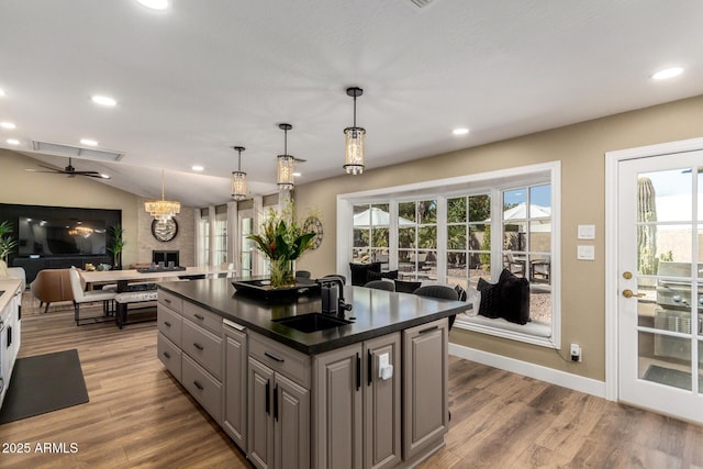 kitchen featuring dark countertops, wood finished floors, vaulted ceiling, gray cabinets, and a sink