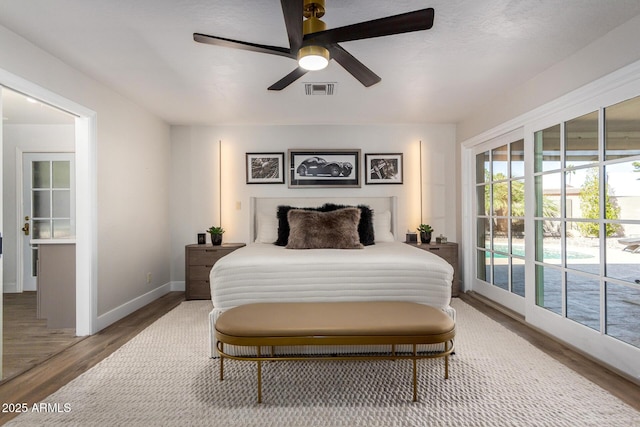 bedroom with access to outside, visible vents, baseboards, and wood finished floors