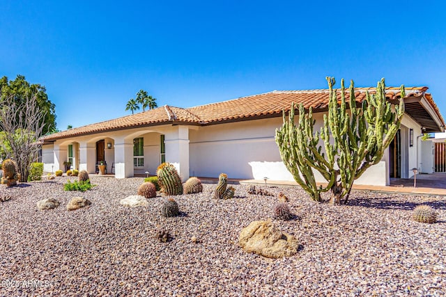 mediterranean / spanish house featuring a tile roof, an attached garage, and stucco siding