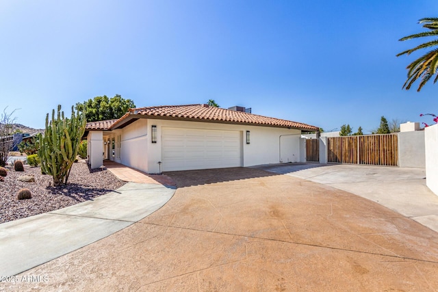 mediterranean / spanish-style house featuring driveway, a tile roof, fence, and stucco siding