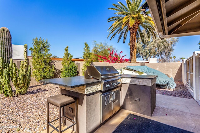 view of patio featuring a fenced backyard, an outdoor kitchen, and area for grilling