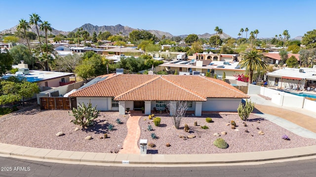 view of front of house with a residential view, a mountain view, a tiled roof, and fence