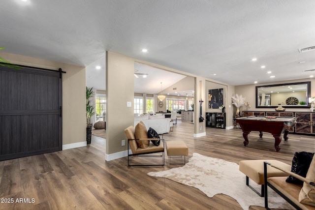 living room featuring a barn door, baseboards, visible vents, wood finished floors, and pool table