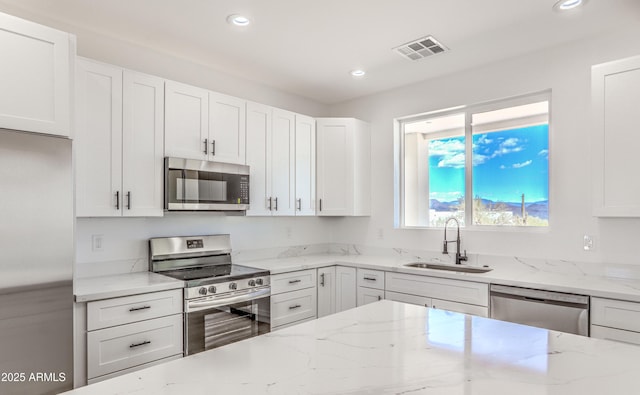 16025 E Rancho Laredo Dr, Scottsdale, AZ 85262 - kitchen with stainless steel appliances, a sink, white cabinets, recessed lighting, and light stone counters