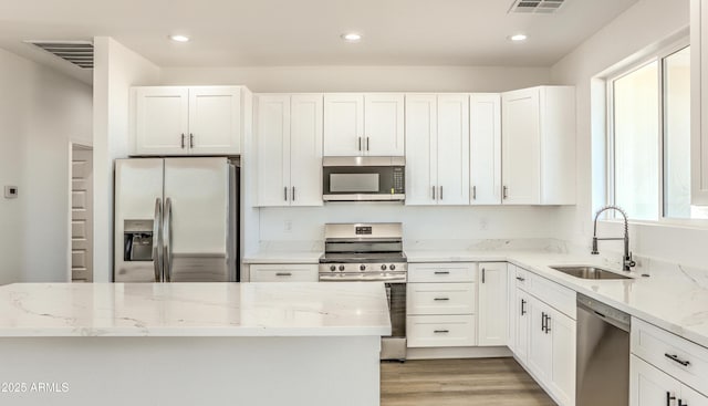16025 E Rancho Laredo Dr, Scottsdale, AZ 85262 - kitchen with appliances with stainless steel finishes, a sink, light stone counters, light wood-style floors, and white cabinetry