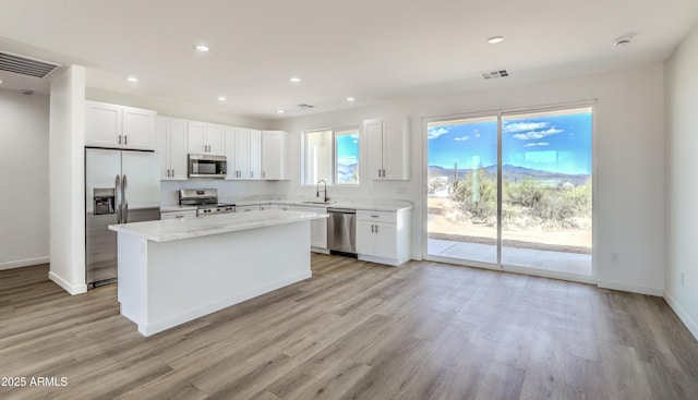 16025 E Rancho Laredo Dr, Scottsdale, AZ 85262 - kitchen with appliances with stainless steel finishes, a sink, a center island, white cabinetry, and light wood-style flooring