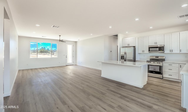 16025 E Rancho Laredo Dr, Scottsdale, AZ 85262 - kitchen with appliances with stainless steel finishes, open floor plan, a center island, light countertops, and light wood finished floors