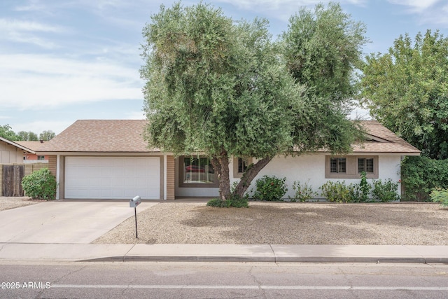 4443 W Acoma Dr, Glendale, AZ 85306 - view of property hidden behind natural elements with driveway, an attached garage, stucco siding, and roof with shingles