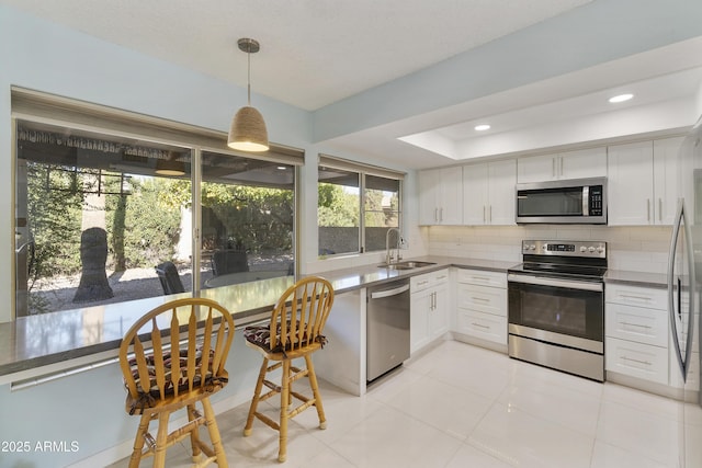 kitchen with decorative light fixtures, sink, white cabinetry, tasteful backsplash, and stainless steel appliances