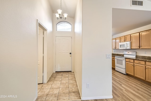 interior space with high vaulted ceiling, light wood-type flooring, and an inviting chandelier