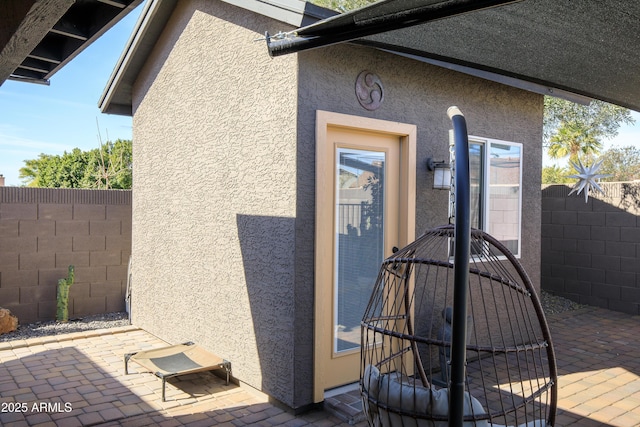 doorway to property with a patio area, fence, and stucco siding