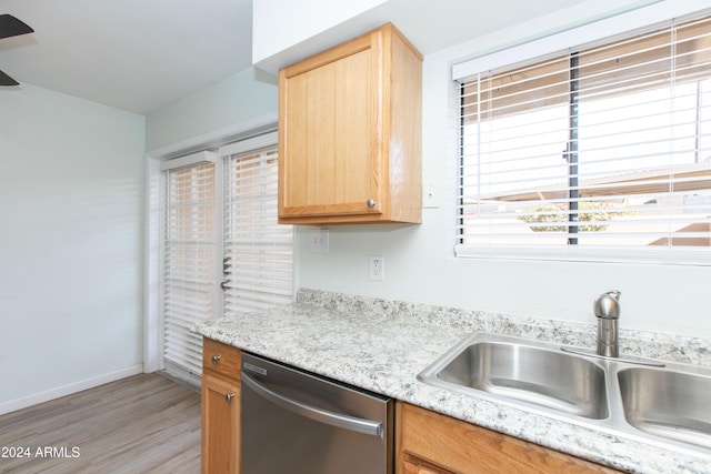 kitchen with light stone countertops, wood-type flooring, stainless steel dishwasher, and sink