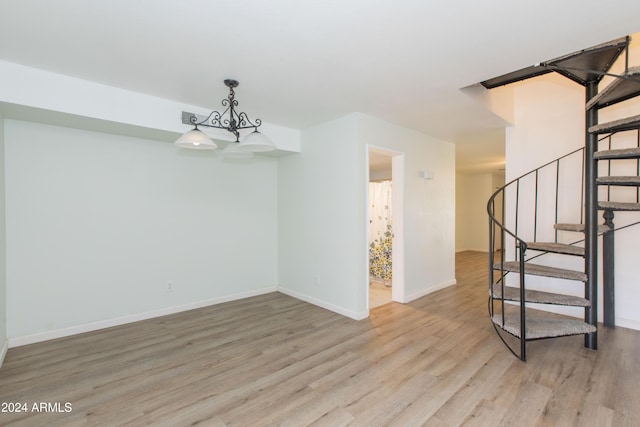 spare room featuring a notable chandelier and light hardwood / wood-style floors