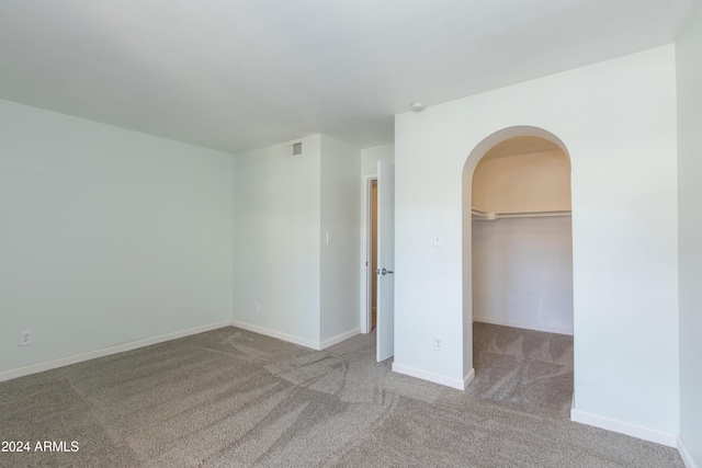 unfurnished bedroom featuring light carpet, a spacious closet, and a closet