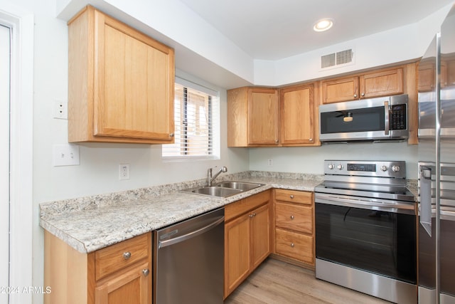 kitchen featuring light stone counters, light wood-type flooring, sink, and appliances with stainless steel finishes