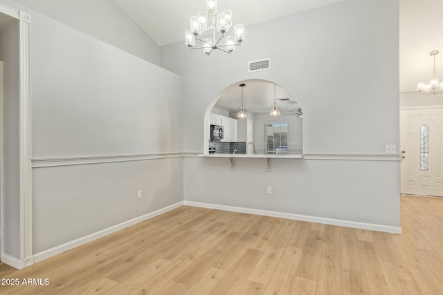 unfurnished dining area with light wood-style floors, visible vents, baseboards, and a notable chandelier