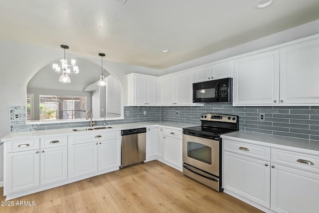 kitchen with decorative backsplash, stainless steel appliances, light wood-style floors, white cabinetry, and a sink