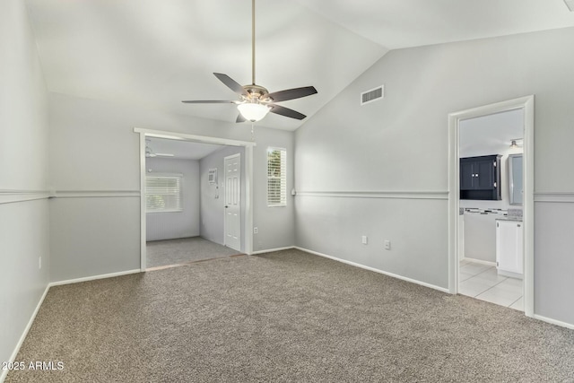 unfurnished bedroom featuring carpet, visible vents, baseboards, lofted ceiling, and ensuite bathroom