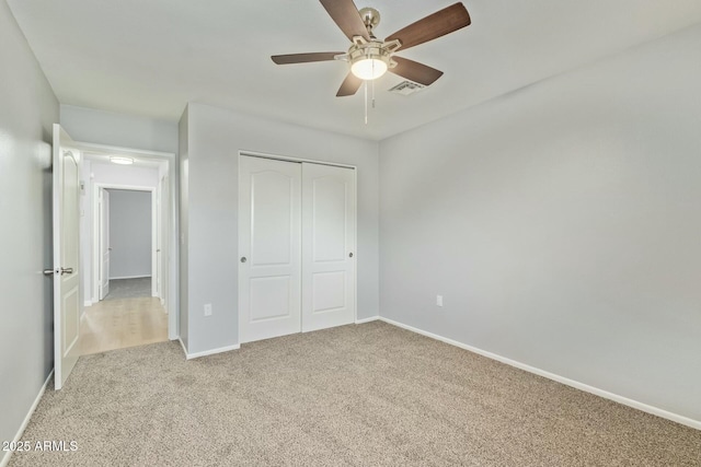 unfurnished bedroom with baseboards, a closet, carpet floors, and visible vents