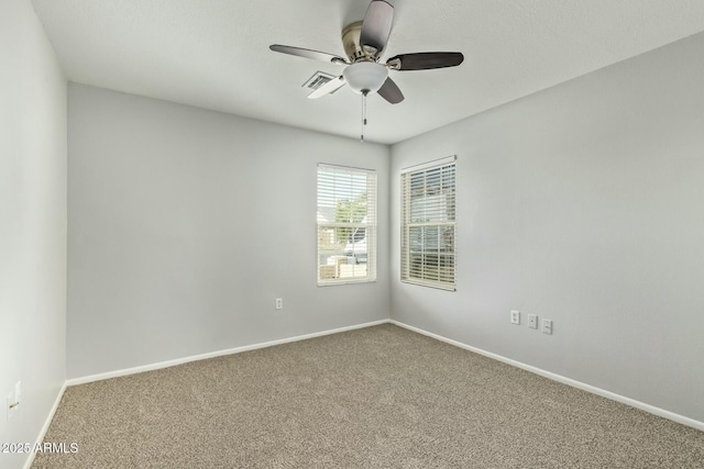 carpeted empty room with visible vents, baseboards, and ceiling fan