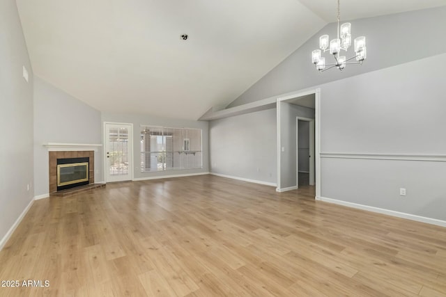 unfurnished living room with a chandelier, a tile fireplace, light wood-type flooring, and baseboards