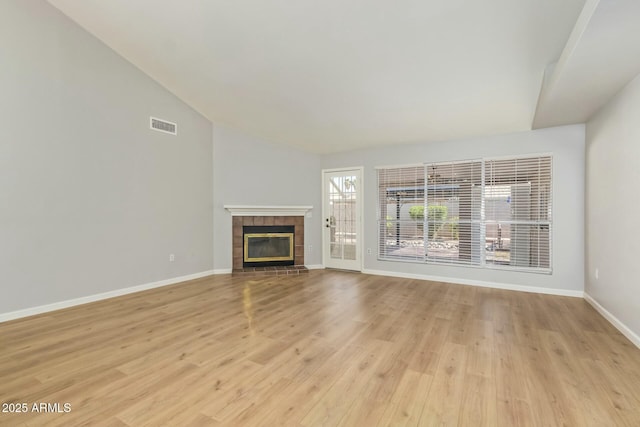 unfurnished living room featuring visible vents, baseboards, light wood-style flooring, a fireplace, and vaulted ceiling