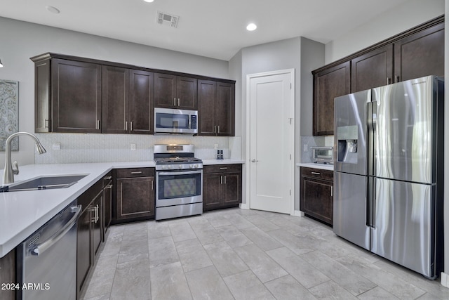 kitchen featuring decorative backsplash, appliances with stainless steel finishes, dark brown cabinets, and sink