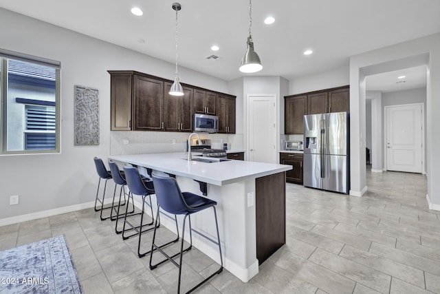 kitchen featuring sink, kitchen peninsula, pendant lighting, a breakfast bar, and appliances with stainless steel finishes