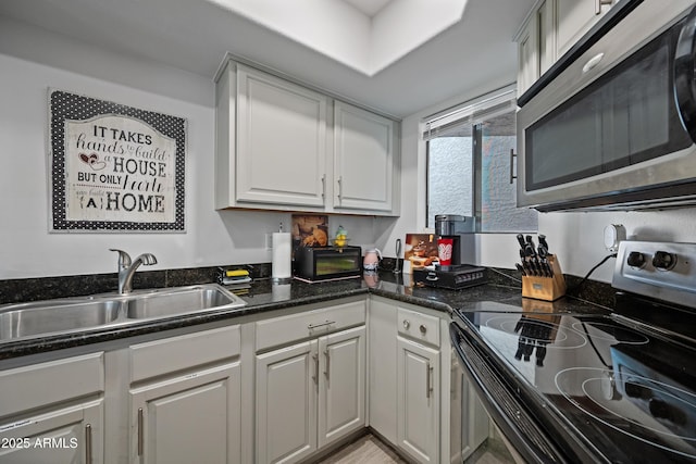 kitchen with a sink, white cabinetry, stainless steel microwave, and electric stove