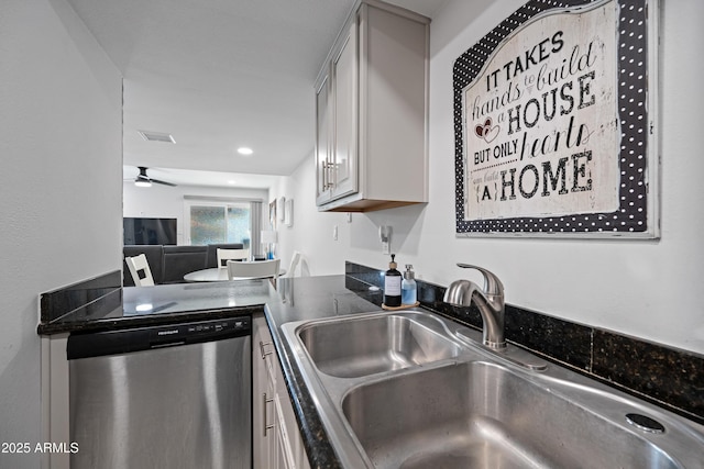 kitchen featuring a ceiling fan, dark countertops, gray cabinetry, stainless steel dishwasher, and a sink