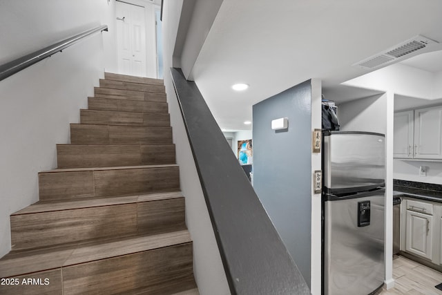 stairway featuring recessed lighting, visible vents, and wood finished floors