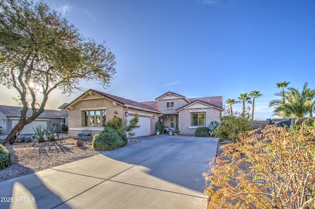 view of front of house with stucco siding, concrete driveway, and an attached garage