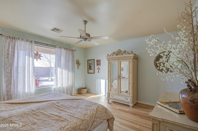 bedroom with light wood-style flooring, baseboards, visible vents, and ceiling fan