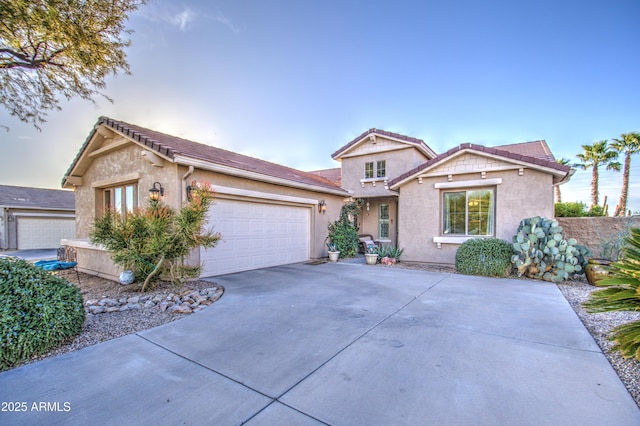 view of front facade with concrete driveway, a tiled roof, an attached garage, and stucco siding