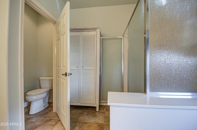 bathroom with tile patterned flooring, a shower stall, toilet, and a closet