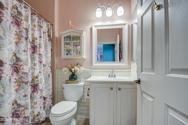 bathroom featuring vanity, a shower with shower curtain, a wainscoted wall, tile walls, and toilet