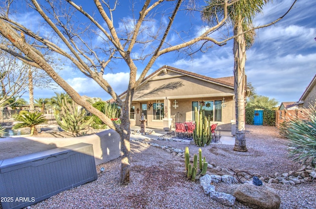 view of front of home with stucco siding, a tiled roof, a patio, and fence