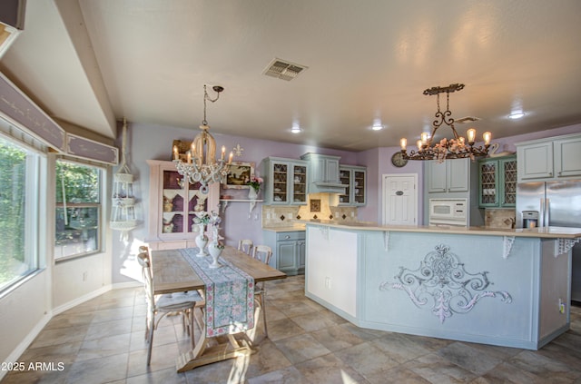 kitchen featuring an inviting chandelier, tasteful backsplash, white microwave, and visible vents