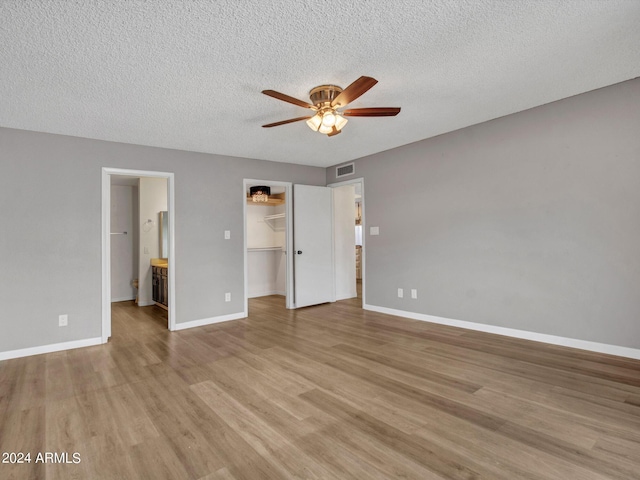 17838 N 45th Ave, Glendale, AZ 85308 - unfurnished bedroom with baseboards, light wood-style flooring, a walk in closet, visible vents, and a textured ceiling