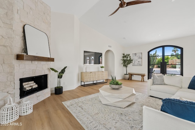 14401 N 60th Pl, Scottsdale, AZ 85254 - living area with a ceiling fan, wood finished floors, a stone fireplace, lofted ceiling, and arched walkways