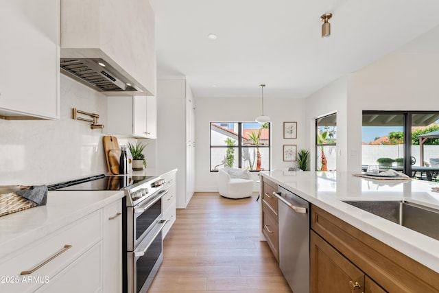 14401 N 60th Pl, Scottsdale, AZ 85254 - kitchen with stainless steel appliances, wall chimney range hood, light countertops, light wood-type flooring, and white cabinetry