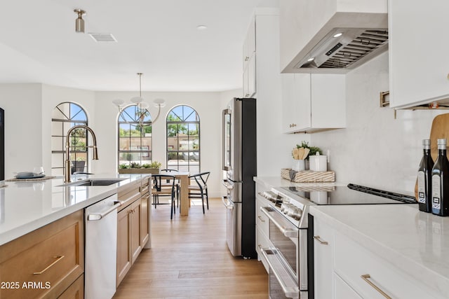 14401 N 60th Pl, Scottsdale, AZ 85254 - kitchen featuring custom range hood, appliances with stainless steel finishes, light wood-style flooring, decorative light fixtures, and brown cabinetry