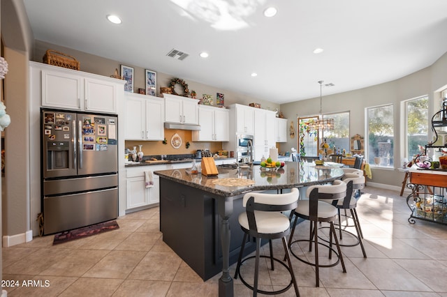 kitchen featuring stainless steel fridge, white cabinets, and an island with sink