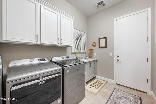 clothes washing area with cabinets, sink, separate washer and dryer, and light tile patterned flooring