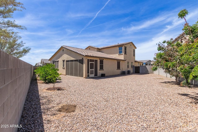 back of property with a sunroom, stucco siding, a tiled roof, and a fenced backyard
